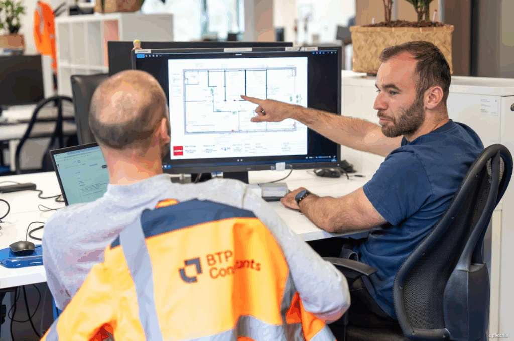 Deux collaborateurs analysant un plan technique sur un écran dans un bureau