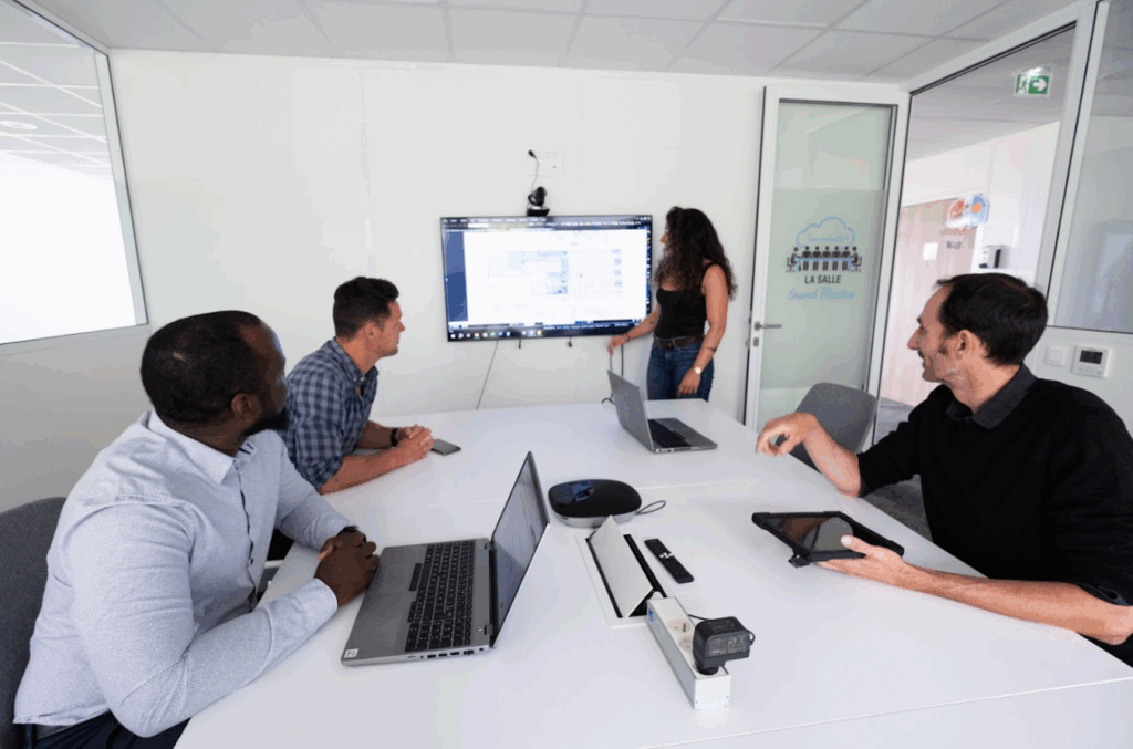 Équipe en réunion dans une salle de travail, présentation projet sur écran