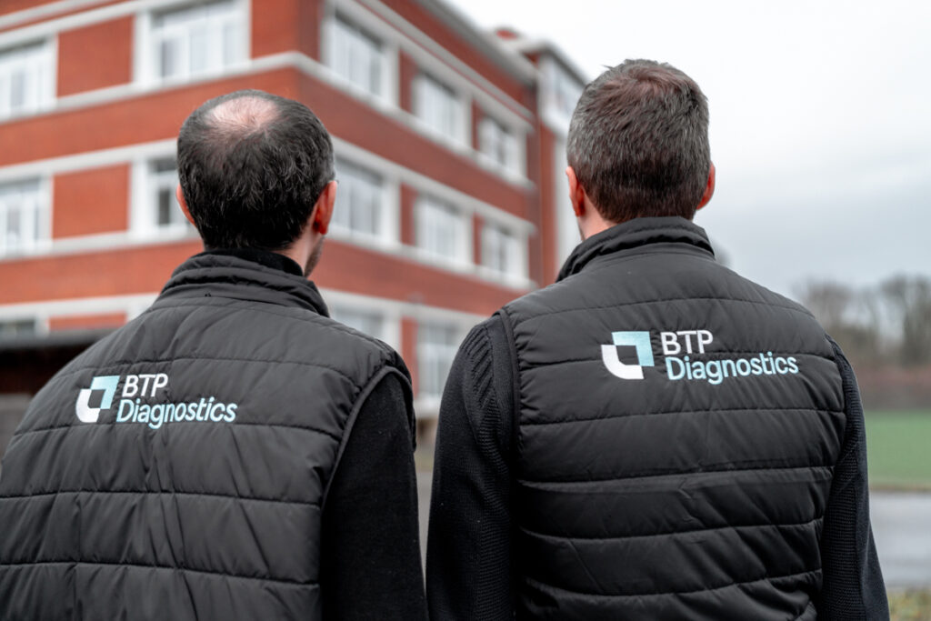 Experts réalisant un Diagnostic Technique Global (DTG) en copropriété devant un immeuble résidentiel